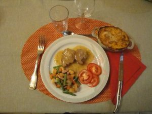 Un plat appétissant avec viande en sauce, jardinières de légumes, rondelle de tomates et gratin.