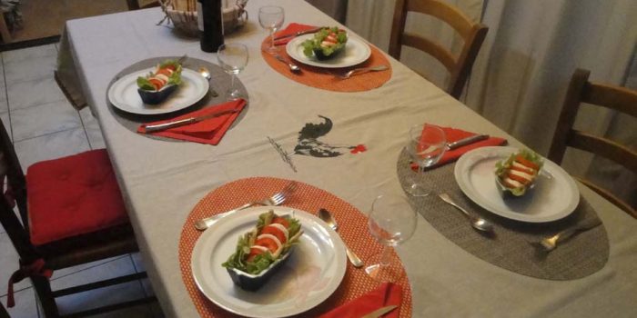 La table du repas avec assiettes, couverts, entrée, vin et corbeille à pain.